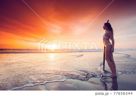 Woman holding surfboard at sunset 77656344