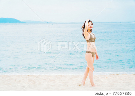 砂浜を歩く水着の女性 77657830