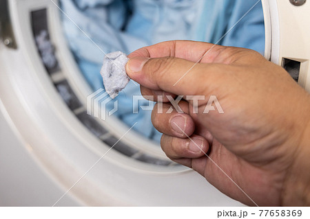 Hand removing lint from fabric trapped on laundry dryer filter 77658369
