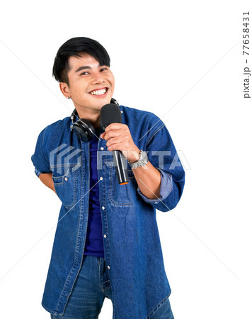 Young asian man in blue jean singing with microphone. Portrait on white background with studio light. Close Up Young asian man in blue jean singing with microphone. Portrait on white background with studio light. Close Up 77658431