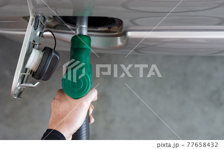 Gas station worker filling up bronze pickup truck tank (Top View). Closeup hand holding green gas pump nozzle. Gas station worker filling up bronze pickup truck tank (Top View). Closeup hand holding green gas pump nozzle. 77658432