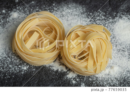 Raw nest noodles with flour on a dark background 77659035