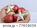 Holding christmas tree balls and stars in the hand 77659039