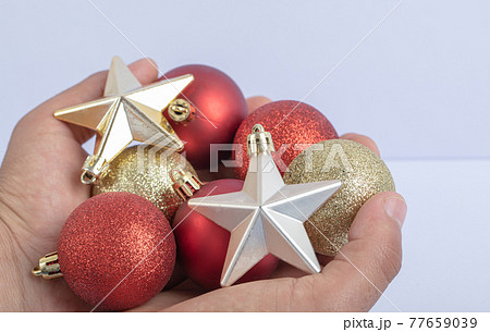 Holding christmas tree balls and stars in the hand 77659039