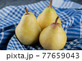 Juicy yellow pears on blue checked kitchen towel 77659043