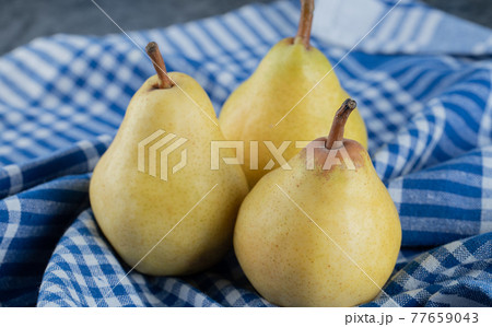 Juicy yellow pears on blue checked kitchen towel 77659043