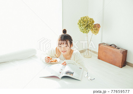 おやつを食べなが雑誌を見る女の子 77659577