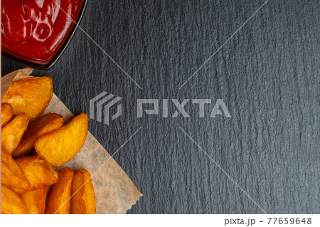 Rustic potato with ketchup on slate, black stone dishes. Top view. 77659648