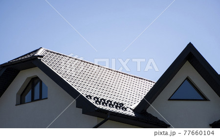 Brown corrugated metal profile roof installed on a modern house. The roof of corrugated sheet. Roofing of metal profile wavy shape. Modern roof made of metal. Metal roofing. 77660104