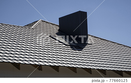 Brown corrugated metal profile roof installed on a modern house. The roof of corrugated sheet. Roofing of metal profile wavy shape. Modern roof made of metal. Metal roofing. Brown corrugated metal profile roof installed on a modern house. The roof of corrugated sheet. Roofing of metal profile wavy shape. Modern roof made of metal. Metal roofing. 77660125