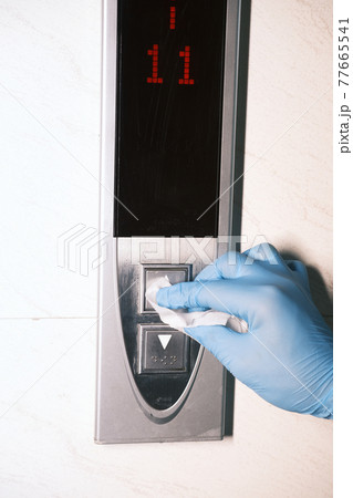 Man hand in protective gloves disinfecting elevator buttons. 77665541