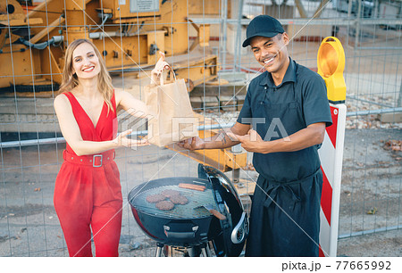 Cook handing woman customer a burger in bag for takeout 77665992