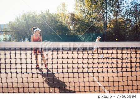 Woman in red sport dress playing tennis 77665994