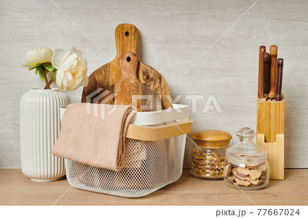 Two wooden chopping boards in a basket next to a vase of flowers 77667024