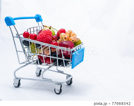 Mini grocery cart filled with fresh vitamin berries isolated on white background 77668342