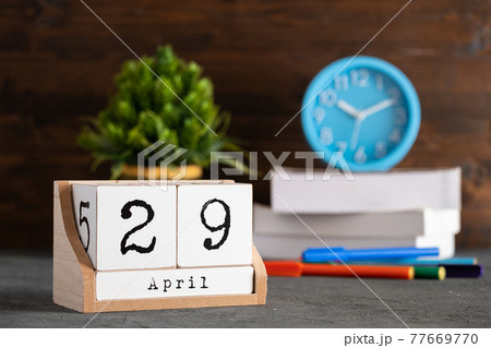 April 29th. April 29 wooden cube calendar with blur objects on background. 77669770
