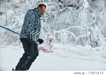 a skier in gray jacket is riding downhill the slope on a frosty day 77671573