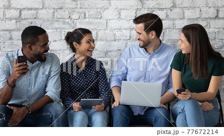 Happy diverse job candidates chatting and laughing while waiting Happy diverse job candidates chatting and laughing while waiting 77672214