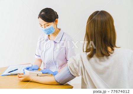 患者の血圧を測る看護師 患者の血圧を測る看護師 77674012