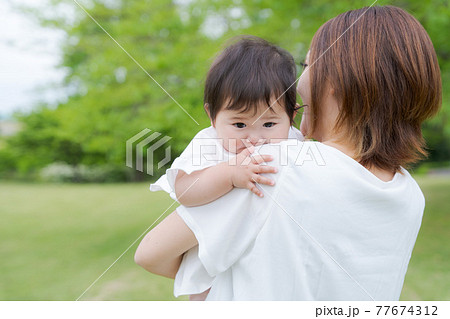 赤ちゃん 抱っこ 緑背景の写真素材