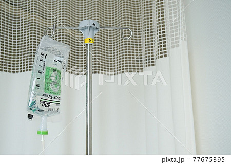 ＜医療＞点滴の輸液パックと病院の白いカーテン 77675395