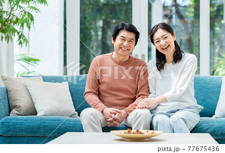 リビングでくつろぐミドルの夫婦 リビングでくつろぐミドルの夫婦 77675436