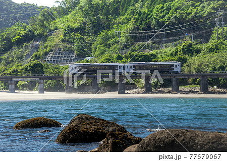 青海と新緑と砂浜を舞い上がる砂嵐を浴び細田川の鉄橋を渡る日南線特急海幸山幸 77679067
