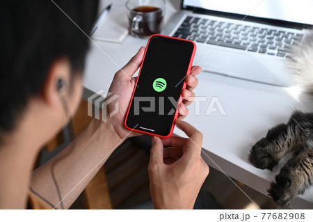 Chiang Mai, Thailand - May 13, 2021 : Man holding iPhone 11 Pro Max with spotify app. Spotify is a music service that offers legal streaming music. Chiang Mai, Thailand - May 13, 2021 : Man holding iPhone 11 Pro Max with spotify app. Spotify is a music service that offers legal streaming music. 77682908