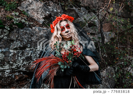 Closeup portrait of Calavera Catrina. Young woman with sugar skull makeup and red flowers. Dia de los muertos. Day of The Dead. Halloween. 77683818