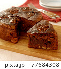 木のまな板にのったくるみのガトーショコラ（チョコレートケーキ） 77684308