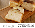 焼き立て食パンのスライスと木のカッティングボード 77684310