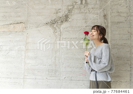 笑顔で薔薇の匂いを嗅ぐ若い女性 笑顔で薔薇の匂いを嗅ぐ若い女性 77684461
