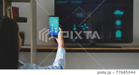 A young woman is using a smartphone with a controlled application. Smart home concept. 77685044