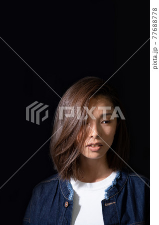 黒背景の白いTシャツにジージャンを着た若い女性の顔のアップ 黒背景の白いTシャツにジージャンを着た若い女性の顔のアップ 77688778