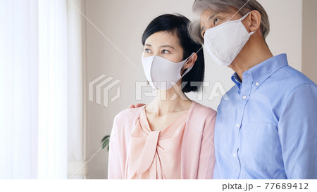 マスクをして不安そうな表情のシニア夫婦 マスクをして不安そうな表情のシニア夫婦 77689412