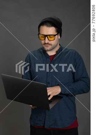 Young hipster man in business casual work remote, dark background, freelance 77692806