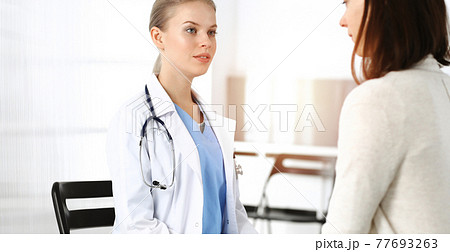 Woman - doctor consults her female patient in sunny clinic 77693263