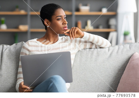 Portrait Of Pensive African Woman Sitting With Laptop On Couch At Home Portrait Of Pensive African Woman Sitting With Laptop On Couch At Home 77693578