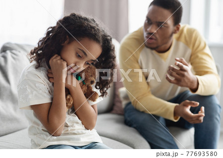 Furious black dad shouting at his frightened little daughter Furious black dad shouting at his frightened little daughter 77693580