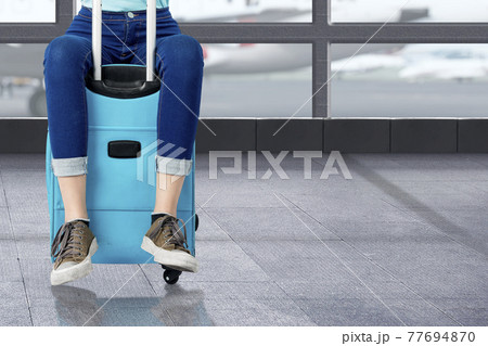 The woman sitting on suitcase The woman sitting on suitcase 77694870