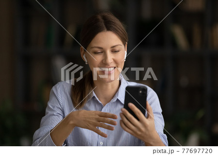 Young woman wear earphones listen to music speak by videocall Young woman wear earphones listen to music speak by videocall 77697720