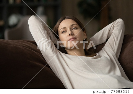 Tranquil teenage female lie on couch with hands behind head Tranquil teenage female lie on couch with hands behind head 77698515