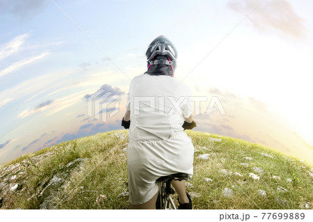 Rear view of Asian woman with a bicycle helmet riding a bicycle Rear view of Asian woman with a bicycle helmet riding a bicycle 77699889