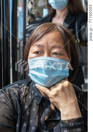 Mature asian woman wearing a mask on a bus: Selective focus. Safety and new public transport rules concept. 77700303