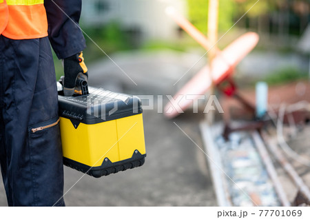 Worker hand carrying tool box at construction site 77701069