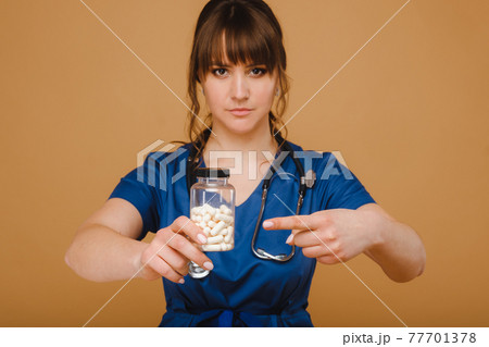 white pills in a jar of a female doctor. The doctor shows the vitamin capsules.Medicinal capsules. white pills in a jar of a female doctor. The doctor shows the vitamin capsules.Medicinal capsules. 77701378