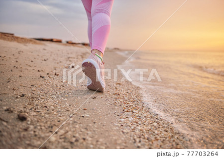 Closeup of female athlete runner feet along a sea coastline 77703264