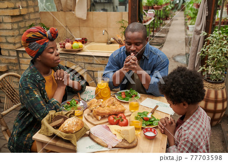 Family praying at the table 77703598