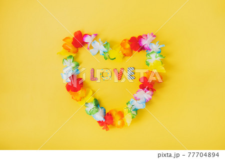 Hawaiian flower necklace in the shape of heart with word Love inside on the yellow background. Summer background. LGBT concept with rainbow flag colors. Selective focus. Copy space. Hawaiian flower necklace in the shape of heart with word Love inside on the yellow background. Summer background. LGBT concept with rainbow flag colors. Selective focus. Copy space. 77704894