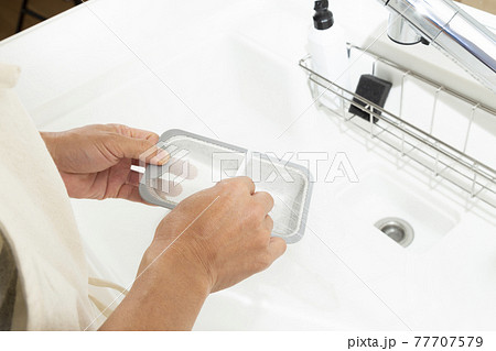 キッチンで水切りネットを付ける男性の手元 77707579